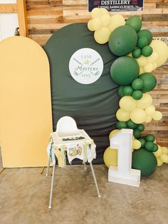 a table and chair are set up in front of a large balloon arch with the number one on it