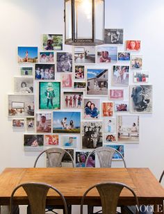 a dining room table with chairs and pictures on the wall above it, along with two pendant lights