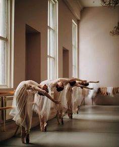 three ballet dancers in white tulle skirts are lined up on the floor