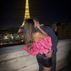 a man and woman kissing in front of the eiffel tower at night time