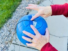 a person holding onto a blue ball on the ground