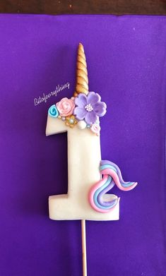 a birthday cake shaped like a unicorn with flowers on it's head and the number one