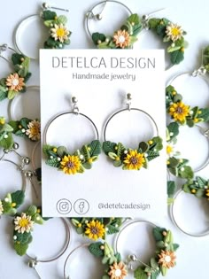 the earrings are decorated with sunflowers and green leafy leaves on hoop ear wires