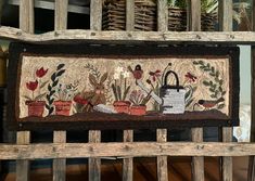 an old wooden bench with a rug on it that has flowers, plants and a watering can