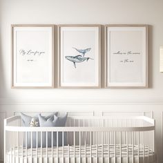 three framed pictures hang on the wall above a crib in a white nursery room