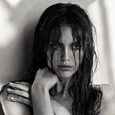 black and white photograph of a woman with wet hair posing in front of a wall