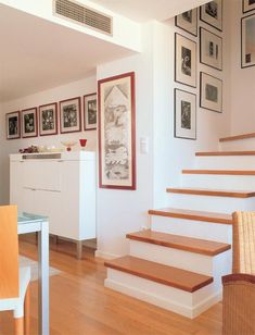 there are pictures on the wall above the stairs in this living room and dining area