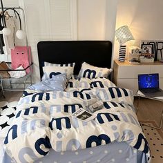 a bed with blue and white comforters in a bedroom next to a laptop computer