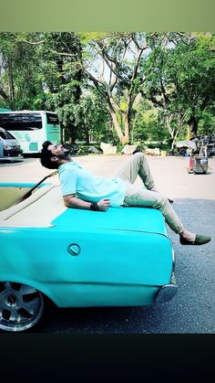 a man laying on top of a blue car