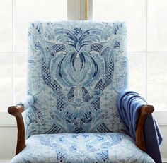 a blue chair sitting in front of a window with a blanket on top of it