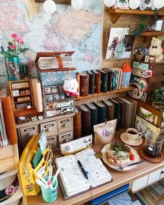 a desk with lots of books and other items on top of it in front of a map