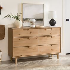 a wooden dresser with two vases and a painting on the wall in front of it