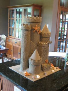 a castle made out of sand sitting on top of a black countertop next to a dining room table