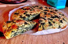 a cheese and spinach quiche cut in half on a cutting board with one slice missing