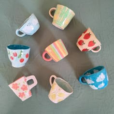 there are many different cups on the table together, all painted in different colors and designs