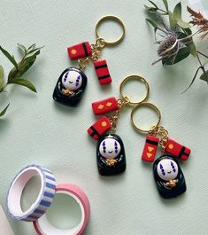 four key chains with cartoon characters on them sitting next to a cup and flower pot