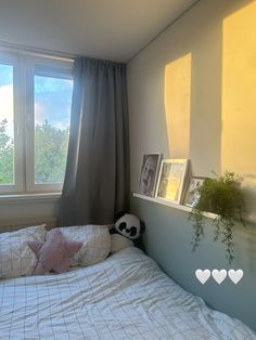 a bedroom with a bed, window and pictures hanging on the wall next to it