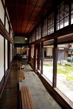 an empty room with wooden benches and windows on both sides, looking out onto the yard