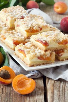 several pieces of dessert sitting on top of a white plate next to peaches and other fruit