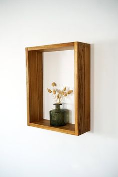 a vase with flowers in it sitting on a shelf next to a wall mounted mirror