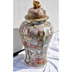 Large ceramic floor vase or urn features Chinese Famille Rose chinoiserie hand painted body in vivid enamel colors depicting Oriental Senes along with birds and flora. Domed lid features a gold foo dog as handle. Maker's mark present on bottom. Excellent condition free of chips, cracks, or repairs.   Measures:  27"H - 35"H with lid 17"D  17"W 53" in Diameter at the widest part of the vase Foo Dog, Ceramic Floor, Floor Vase, Early 20th Century, Makers Mark, Chinoiserie, 20th Century, Porcelain, Vase