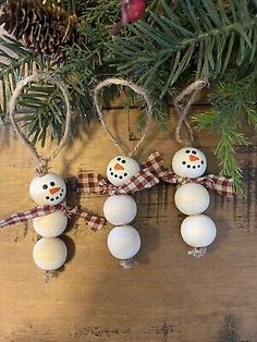 three snowman ornaments hanging from a christmas tree