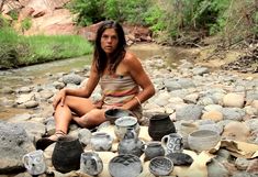 a woman is sitting on the ground with pots and pans in front of her