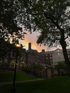 the sun is setting over an old brick building and some trees in front of it