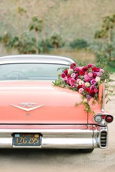 an old pink car with flowers on the back