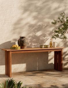 a wooden table sitting next to a potted plant on top of a cement floor