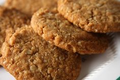 three oatmeal cookies sitting on top of a white plate next to a green and white napkin