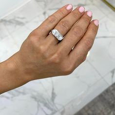 a woman's hand with a diamond ring on her left wrist, in front of a marble floor