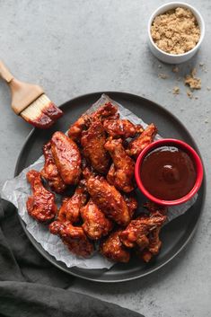 chicken wings on a plate with ketchup and seasoning next to the bowl