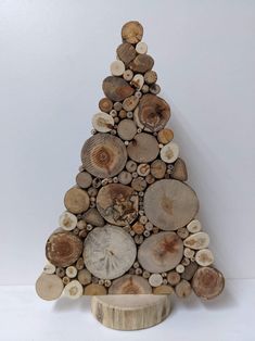 a small christmas tree made out of wood slices and logs is displayed on a white background