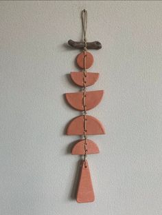 a wall hanging made out of clay and wood with chains attached to the bottom half of it