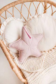 a pink starfish pillow sitting on top of a white blanket in a wicker basket