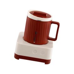 a red and white coffee mug sitting on top of a blender