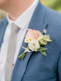 a man wearing a blue suit and white flowers on his lapel flower boutonniere