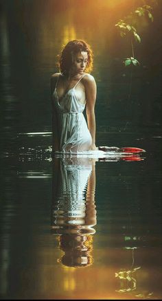 a woman is standing in the water with her reflection