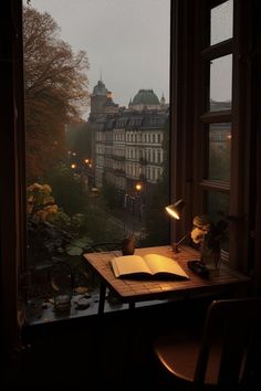 an open book sitting on top of a wooden table next to a window filled with lots of windows