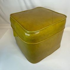 a yellow leather box sitting on top of a white table next to a black cat