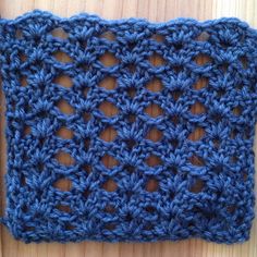 a blue crocheted square sitting on top of a wooden table