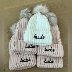 three hats and two mittens that say bride, babe, bab, baby