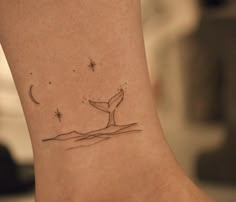 a small tattoo on the ankle of a woman's foot with a whale tail