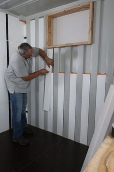 a man standing in front of a white board and batty wall with boards on it