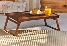 a breakfast tray with croissants and orange juice on it sits on a bed