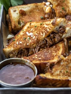 grilled cheese and meat sandwiches with dipping sauces in a pan on a table