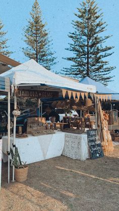 an outdoor market is set up in front of some pine trees and other items for sale