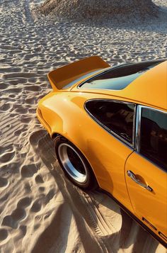 an orange sports car parked in the sand