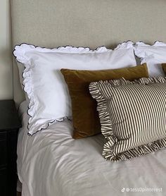 a bed with white sheets and brown pillows